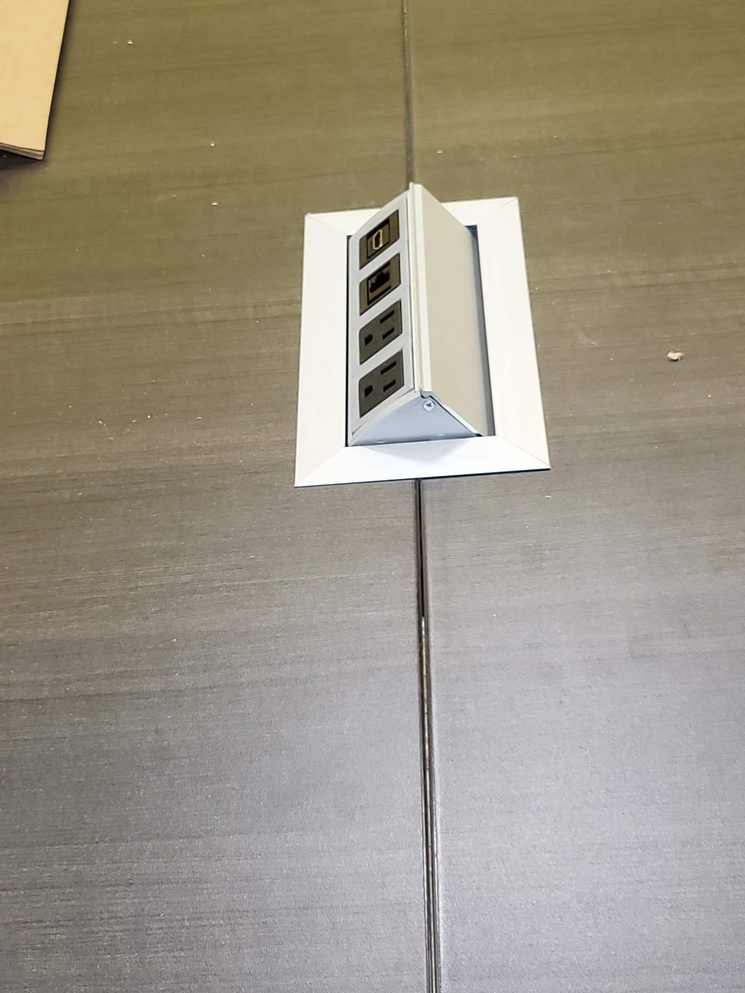 Close-up of a custom-cut conference table power module installed flush with the surface
