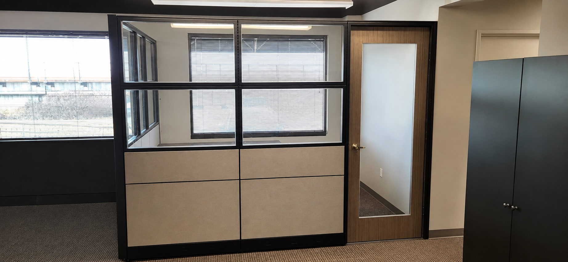 Front view of modular private office panels with glazed upper sections and an integrated access door